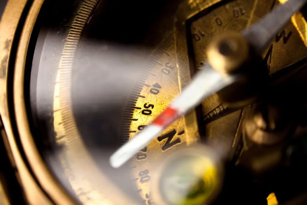Close-up of a compass needle pointing north with light illuminating it.